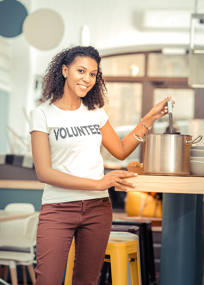 Joyful nice woman helping people as a volunteer