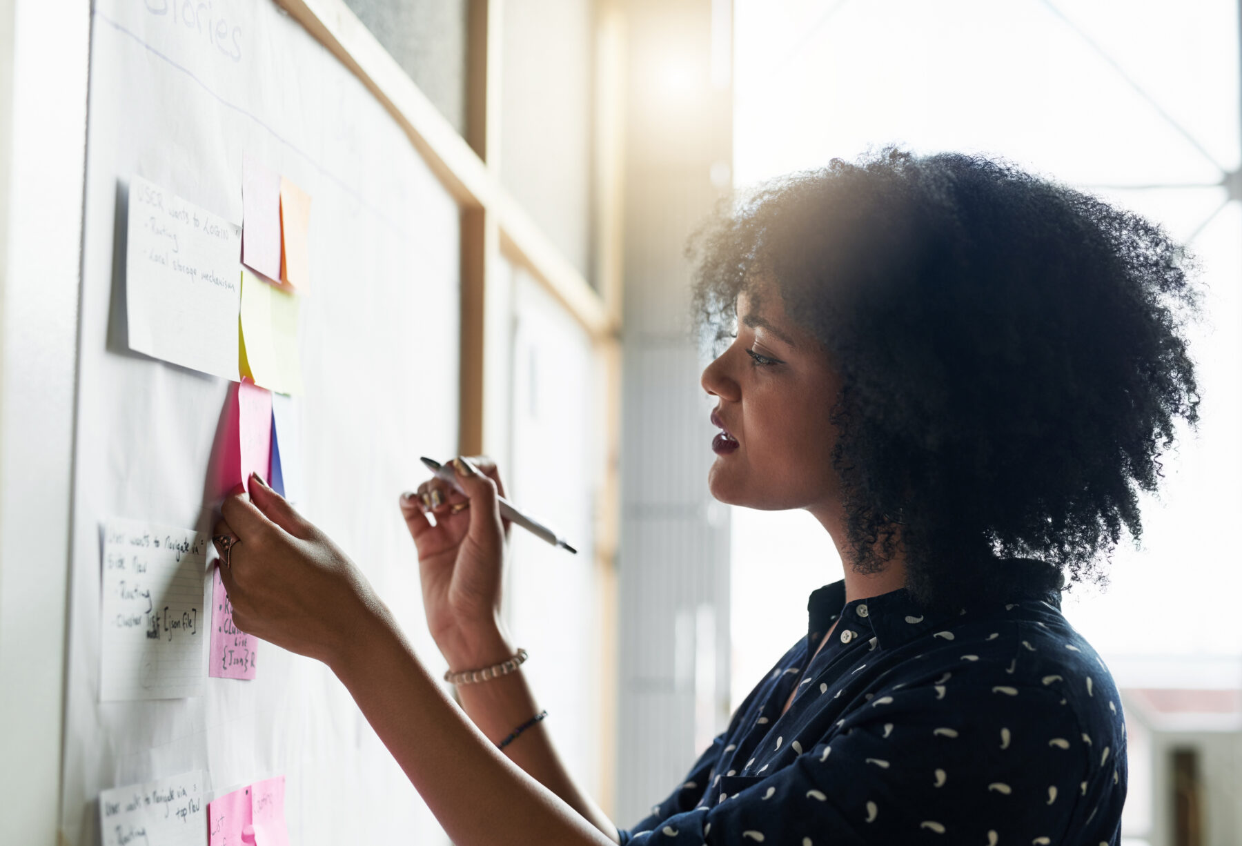 Building a Dashboard for Community Leaders. Image of woman adding sticky note to wall with other notes