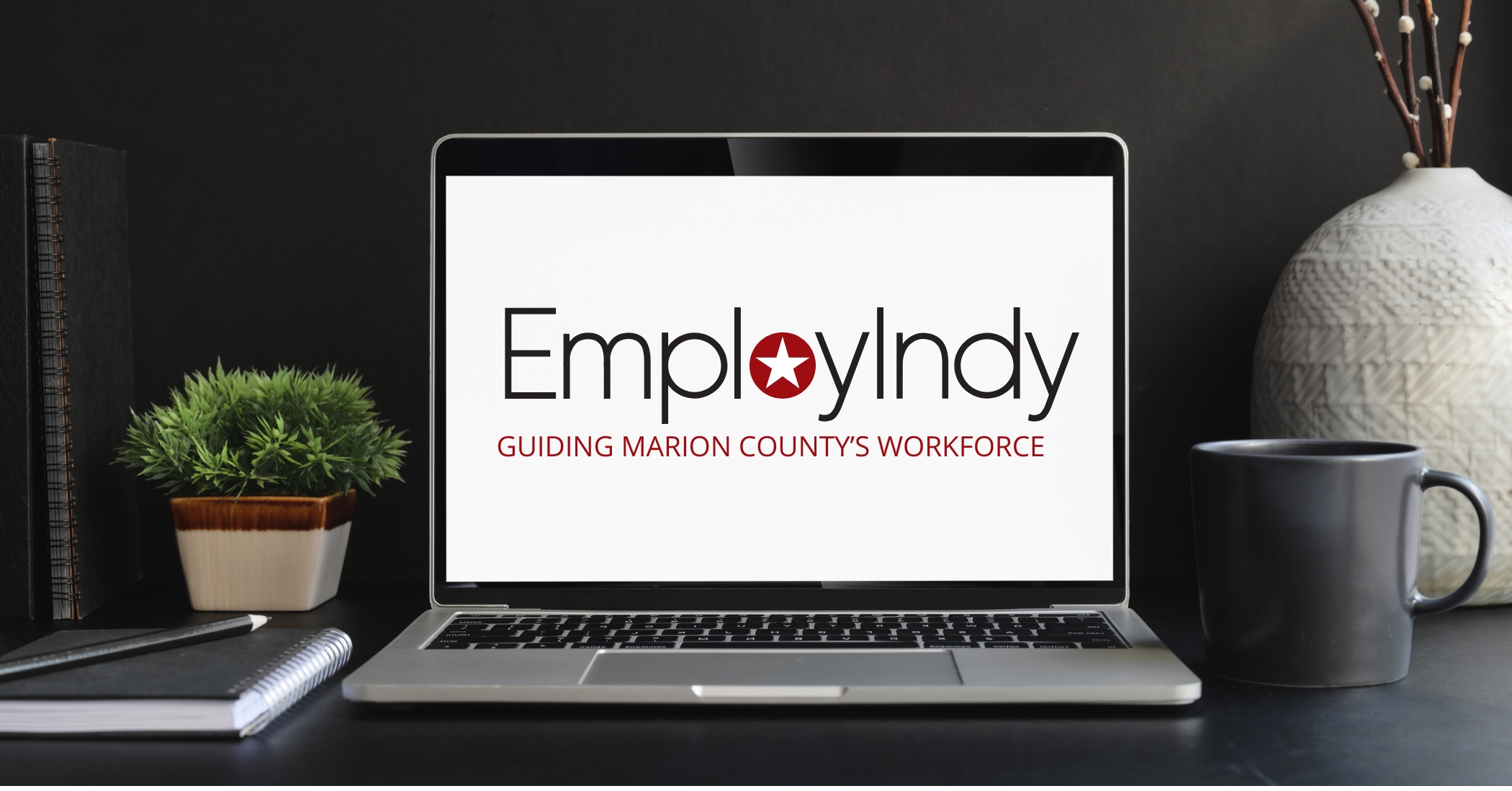 a laptop on a desk with the EmployIndy logo on the screen